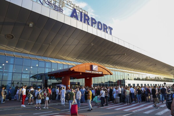 Travelers crowd the entrance to the Chisinau airport in Moldova Friday, June 30, 2023, as it reopened after a lock down prompted by a shooting inside the terminal that left two people dead. A Tajikistan national who was denied entry into Moldova at its main international airport grabbed a guard's weapon and fatally shot two security officers Friday, officials said. One traveler also was wounded.(AP Photo/Aurel Obreja)