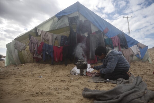 A Palestinian child displaced by the Israeli ground offensive on the Gaza Strip makes tea at a makeshift tent camp in Rafah, Gaza Strip, Sunday, Feb. 18, 2024. (AP Photo/Mohammed Dahman)