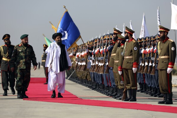 Mullah Abdul Ghani Baradar, the Taliban-appointed deputy prime minister for economic affairs, center, inspects the honor guards during a military parade to mark the third anniversary of the withdrawal of U.S.-led troops from Afghanistan, in Bagram Air Base in the Parwan Province of Afghanistan, Wednesday, Aug. 14, 2024. (AP Photo/Siddiqullah Alizai)