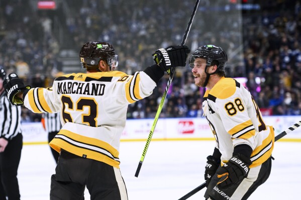 Boston Bruins left wing Brad Marchand (63) and right wing David Pastrnak (88) celebrate Marchand's overtime goal against the Toronto Maple Leafs in an NHL hockey game Saturday, Dec. 2, 2023, in Toronto. (Christopher Katsarov/The Canadian Press via AP)