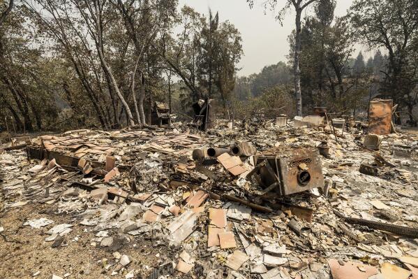 Debris rests at a scorched Gregory Creek Acres home in unincorporated Shasta County, Calif., as the Salt Fire burns nearby on Friday, July 2, 2021. (AP Photo/Noah Berger)