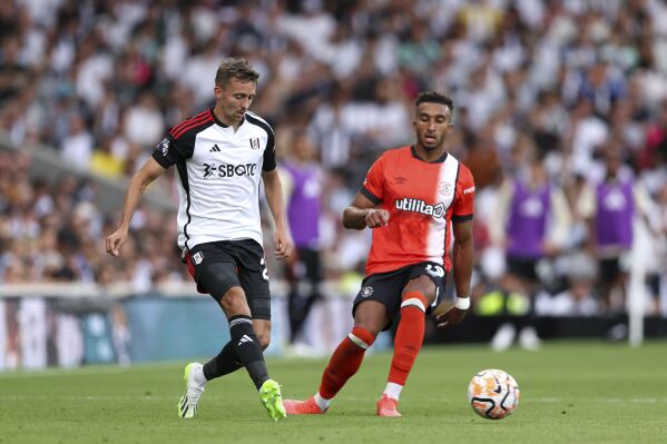 Fulham's Timothy Castagne, left, and Luton Town's Jacob Brown battle for the ball during their English Premier League soccer match at Craven Cottage, London, Saturday, Sept. 16, 2023. (Kieran Cleeves/PA via AP)