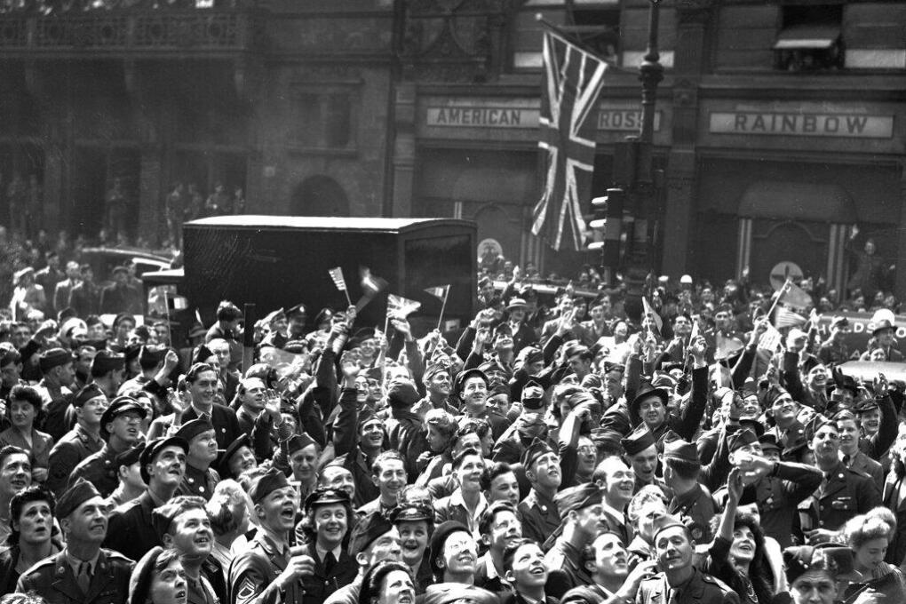 British civilians and Allied service men and women gather, as part of a huge crowd, outside Rainbow Corner, the American Red Cross club, near Piccadilly Circus, London, May 7, 1945, to hear the final announcement of Germany's total surrender. (AP Photo)