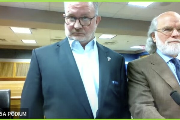 In this image made from video from Judge Scott McAfee's virtual Zoom hearing, Scott Graham Hall, left, stands with his attorney Jeff Weiner, right, in Superior Court of Fulton County before Judge McAfee, not pictured, in Courtroom 5A on Friday, Sept. 29, 2023, in Atlanta. Hall, a bail bondsman charged alongside former President Donald Trump and 17 others in the Georgia election interference case, pleaded guilty to misdemeanor charges on Friday, becoming the first defendant to accept a plea deal with prosecutors. (USA Today via AP, Pool)
