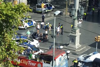 
              Injured are helped by responders as a tour bus passes by after a white van jumped the sidewalk in the historic Las Ramblas district of Barcelona, Spain, crashing into a summer crowd of residents and tourists Thursday, Aug. 17, 2017.   According to witnesses the white van swerved from side to side as it drove into tourists and residents. (Daniel Vil via AP)
            