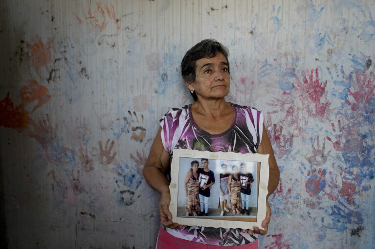 Geronima Benitez holds a photograph of her son Victor Emanuel, 17, who was murdered by drug traffickers who were never arrested two years ago, at her home in Rosario, Argentina, Tuesday, April 9, 2024. Benítez said her son’s killer still lives down her street and is not convinced a prison sentence would make a difference. “We, on the outside, live in prison,” she said. “Those inside have everything.” (AP Photo/Natacha Pisarenko)