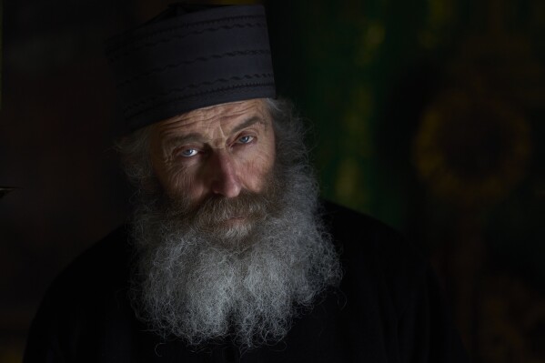 O monge cristão ortodoxo Padre Spyridon olha para dentro da capela do Mosteiro de Panagia Hozoviotissa na ilha de Amorgos, Grécia, na quinta-feira, 27 de março de 2025. (Foto AP/Petros Giannakouris)