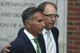 FILE - Clothing designer Mossimo Giannulli, foreground, departs federal court in Boston on Wednesday, April 3, 2019, after facing charges in a nationwide college admissions bribery scandal. Giannulli is asking to serve the remainder of his five-month prison term at home, saying he spent eight weeks in solitary confinement before being transferred to a minimum security camp this week. Giannulli's lawyers said Thursday, Jan. 14, 2021 that Giannulli believed he would only be held in quarantine for a short time before testing negative for the coronavirus. (AP Photo/Charles Krupa, File)