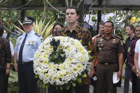Australian Assistant Minister for Foreign Affairs Tim Watts, center, carries a wreath during the commemoration of the 20th anniversary of the Bali bombing that killed 202 people, mostly foreign tourists, including 88 Australians and seven Americans, at the Australian Consulate in Denpasar, Bali, Indonesia on Wednesday, Oct. 12, 2022. Services were held simultaneously in several places in Australia and at Bali's Australian Consulate in the city of Denpasar, where Australian survivors and relatives of the deceased were among the 200 in attendance to pay tribute to their loved ones who died in the most popular tourist area on the island two decades ago. (AP Photo/Firdia Lisnawati, Pool)