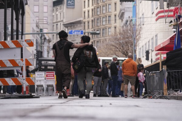 People visit a memorial for victims of the Jan. 1 car attack where newly installed security barriers have since been put in place on Bourbon Street ahead of the Super Bowl in New Orleans, Friday, Jan. 31, 2025. (AP Photo/Gerald Herbert)