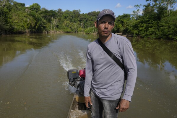 Settler Lincoln Fernandes de Lima steers a boat on the Branco River in an extractive reserve area in Jaci-Parana, Rondonia state, Brazil, Tuesday, July 11, 2023. De Lima said that in September land-grabbers gave him 24 hours to leave his home. (AP Photo/Andre Penner)