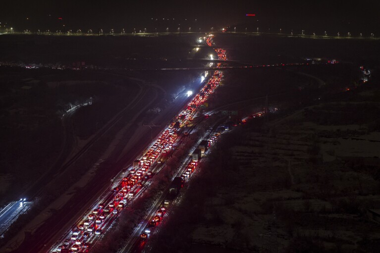 Vehicles are stranded on a snow covered expressway on the outskirts of Wuhan in central China's Hubei province on late Monday, Feb. 5, 2024. Widespread snowfall and freezing weather continued in central and eastern China disrupting transport and stranding travelers amid the annual Lunar New Year travel rush. (Chinatopix via AP)
