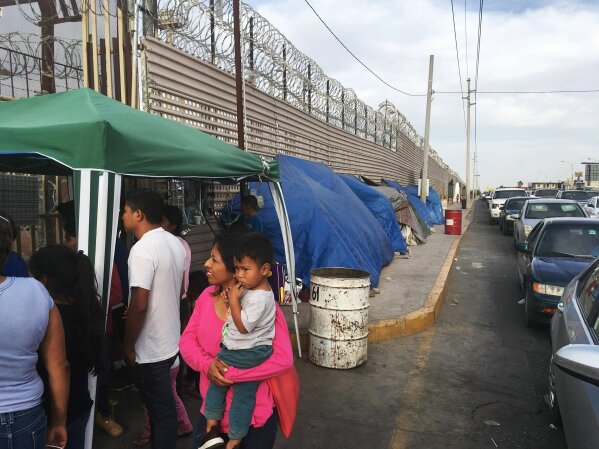 FILE - In this May 5, 2019, file photo, migrants walk between tents, left, and cars waiting to cross the border in San Luis Rio Colorado, Mexico, and Arizona. Newly unsealed court documents show th...