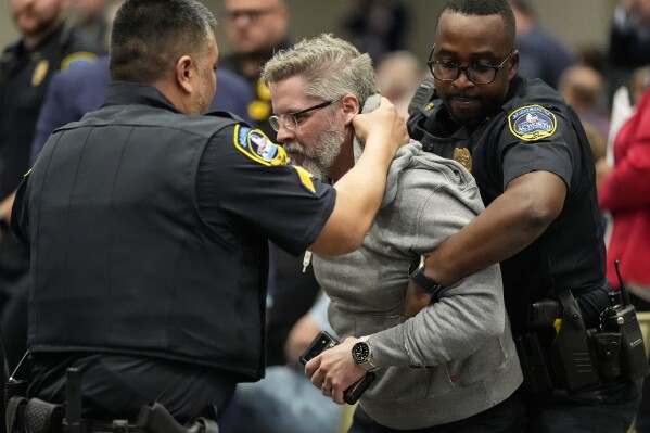 A protester is removed as Rep. Marjorie Taylor Greene, R-Ga., speaks during a town-hall style meeting, in Acworth, Ga., April 15, 2025. (AP Photo/Mike Stewart)