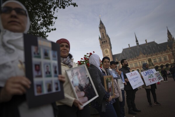 Demonstrators hold pictures of people they say disappeared in Syria outside the World Court, where preliminary hearings opened in a case in which the Netherlands and Canada are suing Syria at the International Court of Justice, or World Court, the United Nations' highest judicial organ, in The Hague, Netherlands, Tuesday, Oct. 10, 2023, accusing Damascus of massive human rights violations against its own people. (AP Photo/Peter Dejong)