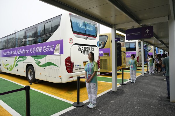 Chinese volunteers stand at a shuttle bus hub at the 19th Asian Games in Hangzhou, China, Tuesday, Sept. 26, 2023. Signs around Hangzhou billed the city as a "paradise on earth" while China adopted the motto "heart to heart" for the games, which attract feature some 12,000 competitors, more than the summer Olympics, from across Asia and the Middle East. (AP Photo/Aaron Favila)