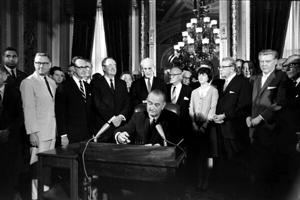 FILE - In this Aug. 6, 1965, photo, President Lyndon B. Johnson signs the Voting Rights Act of 1965 on Aug. 6, 1965, in a ceremony in the President's Room at the U.S. Capitol Washington. Surrounding the president from left directly above his right hand, Vice President Hubert Humphrey; House Speaker John McCormack; Rep. Emanuel Celler, D-N.Y.; first daughter Luci Johnson; and Sen. Everett Dirksen, R-Ill. Behind Humphrey is House Majority Leader Carl Albert of Oklahoma; and behind Celler is Sen. Carl Hayden, D-Ariz. (AP Photo)