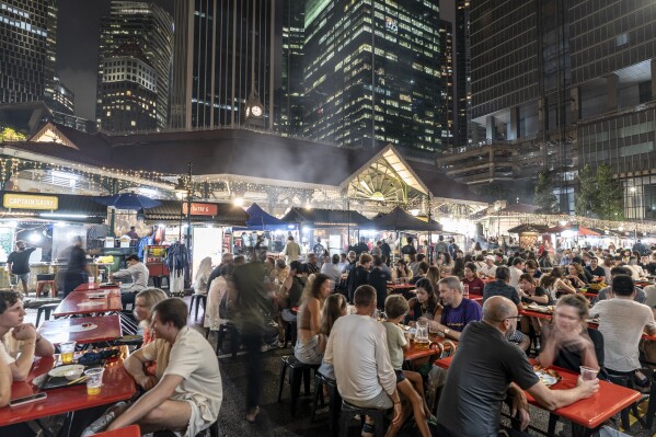 Patrons pack the tables outside the Lau Pa Sat hawker food center surrounded by high-rise buildings in Singapore's financial district, Thursday, July 20, 2023. (AP Photo/David Goldman)