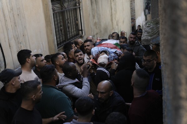 Friends and relatives attend the funeral of Palestinians killed during an Israeli military raid on the Fara'a refugee camp in the West Bank on Monday, Dec. 18, 2023. (AP Photo/Majdi Mohammed)