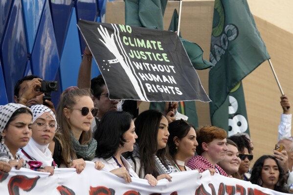 Pro-Palestinian demonstrators participating in a protest against the Israel-Hamas war hold a sign at the COP28 U.N. Climate Summit, Sunday, Dec. 3, 2023, in Dubai, United Arab Emirates. (AP Photo/Peter Dejong)