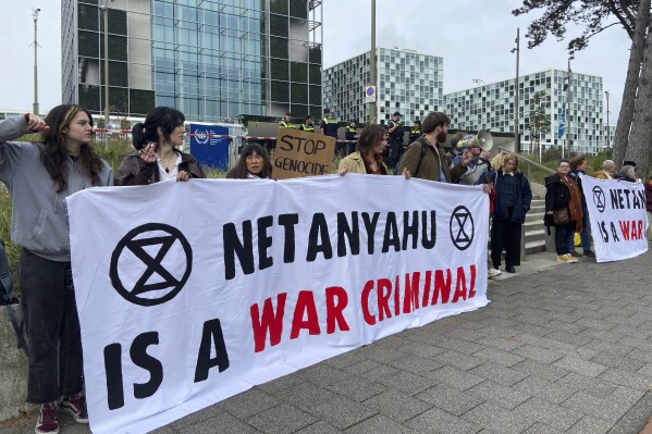 Activists hold up a banner denouncing Israeli Prime Minister Benjamin Netanyahu for Israel’s actions during the war with Hamas as they demonstrate at the entrance of the International Criminal Court in The Hague, Netherlands, Monday, Oct. 23, 2023. Dutch authorities detained 19 activists who occupied the entrance to court. (AP Photo/Aleks Furtula)