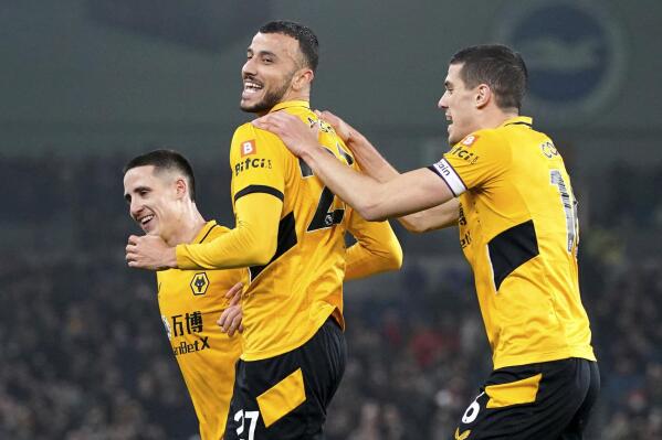 Wolverhampton Wanderers' Romain Saiss, center, celebrates scoring with teammates during the English Premier League soccer match between Brighton & Hove Albion and Wolverhampton Wanderers at AMEX Stadium, Brighton, England, Wednesday Dec. 15, 2021. (Gareth Fuller/PA via AP)
