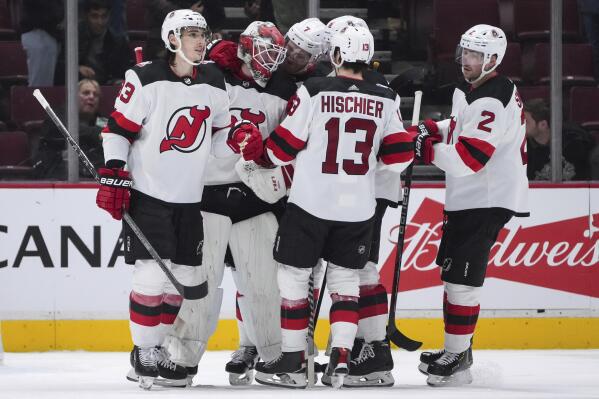 New Jersey Devils' Ryan Graves, goalie MacKenzie Blackwood, Dougie Hamilton, John Marino, Nico Hischier and Brendan Smith, from left, celebrate the team's win over the Vancouver Canucks in an NHL hockey game Tuesday, Nov. 1, 2022, in Vancouver, British Columbia. (Darryl Dyck/The Canadian Press via AP)