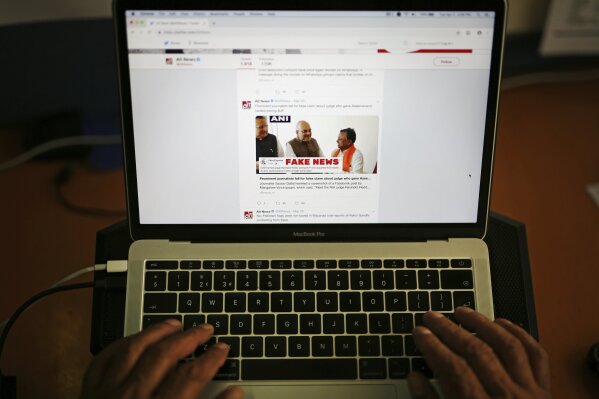 FILE - In this Tuesday, April 2, 2019, file photo, a man browses through the Twitter account of Alt News, a fact-checking website. A new survey says half of U.S. adults consider fake news a major problem, and they mostly blame politicians and activists for it. (AP Photo/Altaf Qadri, File)