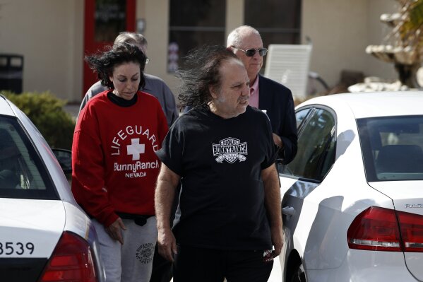 
              Ron Jeremy, front right, and Heidi Fleiss, left, walk out of the Love Ranch brothel, Tuesday, Oct. 16, 2018, in Pahrump, Nev. Dennis Hof, a pimp who gained notoriety for an HBO series about his brothel business, was found dead hours after his 72nd birthday bash, authorities said Tuesday. Hof had said his party would be attended by porn star Jeremy. It wasn't immediately clear Tuesday if Jeremy attended. Hof upended Nevada politics this summer when he ousted an incumbent Republican lawmaker in a primary, celebrating at an election night party with "Hollywood Madam" Fleiss. (AP Photo/John Locher)
            