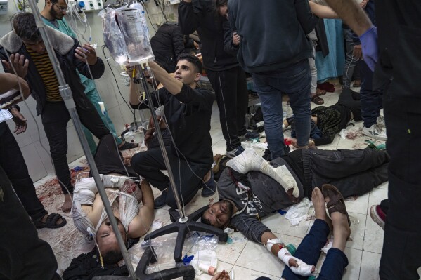 Palestinians are treated as they lie on the floor after being wounded in an Israeli army bombardment of the Gaza Strip, in the hospital in Khan Younis, Tuesday Dec. 5, 2023. (AP Photo/Fatima Shbair)
