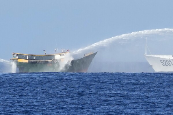 FILE - Philippine resupply vessel Unaizah May 4, left, is hit by two Chinese coast guard water canons as they tried to enter the Second Thomas Shoal, locally known as Ayungin Shoal, in the disputed South China Sea on March 5, 2024. For the first time, China has publicized what it claims is an unwritten 2016 agreement with the Philippines over access to South China Sea islands. (AP Photo/Aaron Favila, File)