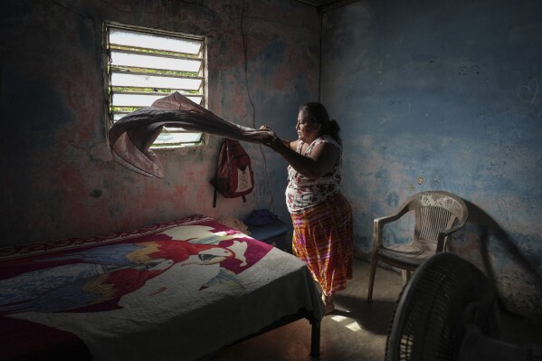 Climate refugee Áurea Sánchez makes the bed inside the home she is renting, in Frontera, in the state of Tabasco, Mexico, Thursday, Nov. 30, 2023. Sanchez and her family were driven from their home when flooding driven by a Gulf of Mexico sea-level rise destroyed their coastal community of El Bosque. (AP Photo/Felix Marquez)