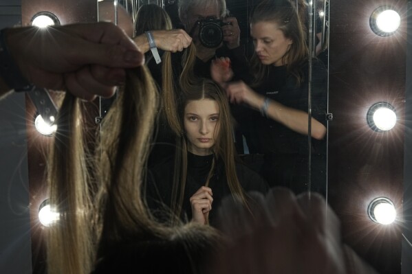 Make-up artists prepare a model, center, to show the Belgian-Argentine label Sadaels collection backstage in a Parking Gallery at Zaryadye Park near the Kremlin in Moscow, Russia, Tuesday, Nov. 28, 2023. An international fashion forum in Moscow has brought together designers from Brazil, China, India, South Africa and other countries, an event that underlined Russia's shift away from the West amid the fighting in Ukraine. (AP Photo/Alexander Zemlianichenko)