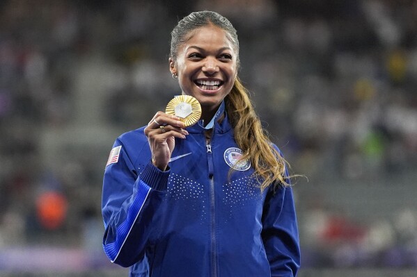 Gold medalist Gabby Thomas stands on the podium after the women's 200-meter at the 2024 Summer Olympics, Wednesday, Aug. 7, 2024, in Saint-Denis, France. (AP Photo/Matthias Schrade, File)