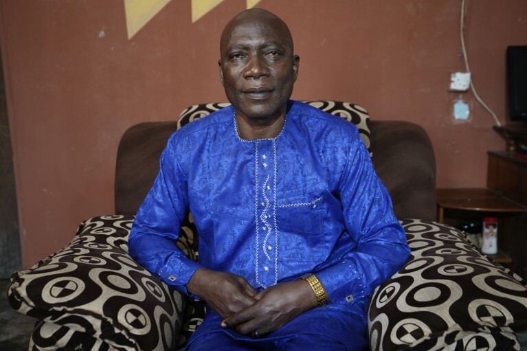 Patrick Aganyebi, a maintenance operator aboard the Trinity Spirit oil ship, sits for a portrait in his home in Igbokoda, Nigeria, on Tuesday, Sept. 6, 2022. It was the dead of night when the Trinity Spirit caught fire, Aganyebi remembers, but the flames made it seem as bright as day. Months afterward, his eyes were still damaged from the glare. He tucked his phone and ID card in his pockets, strapped on a life jacket and made his way to the upper deck, and as the flames barreled toward him, prepared to jump nearly 100 feet (30 meters) into the sea. (AP Photo/Sunday Alamba)