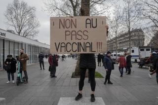 Una persona sostiene un cartel con el mensaje "¡No al pase de vacunas!" en una protesta contra el pase de vacunas contra el COVID-19, en París, Francia, el sábado 22 de enero de 2022. (AP Foto/Rafael Yaghobzadeh)