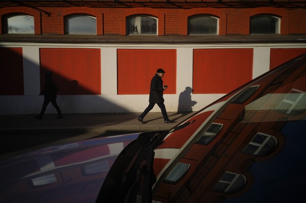 People walk in a street on a sunny day in Moscow, Russia, Tuesday, Feb. 25, 2025. (AP Photo/Pavel Bednyakov)