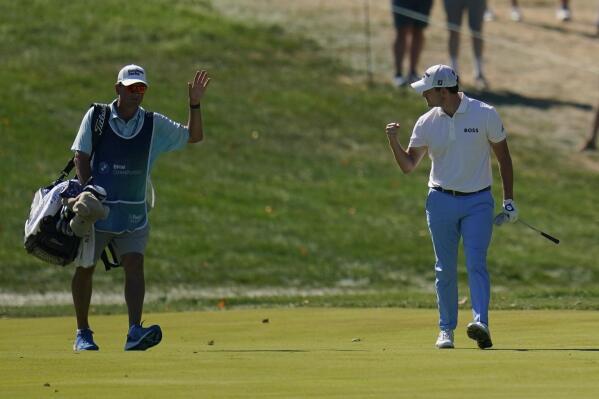 Patrick Cantlay, right, celebrates with his caddie after he holed out from the fairway on the 14th hole during the third round of the BMW Championship golf tournament at Wilmington Country Club, Saturday, Aug. 20, 2022, in Wilmington, Del. (AP Photo/Julio Cortez)