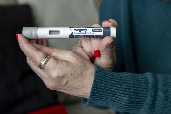 FILE - Donna Cooper holds up a dosage of Wegovy, a drug used for weight loss, at her home, March 1, 2024, in Front Royal, Va. The popular weight-loss drug Wegovy may be paid for by Medicare — as long as patients using it also have heart disease and need to reduce the risk of future heart attacks, strokes and other serious problems, federal officials said Thursday, March 21. (AP Photo/Amanda Andrade-Rhoades, File)