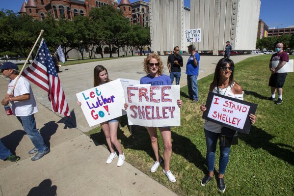 From center left, Kate Lockhart, her mother, Julia Lockhart, and Kristi Lisenbee gather with other protesters to call for the release of jailed salon owner Shelley Luther in front of the Dallas Municipal Court building in downtown Dallas, Wednesday, May 6, 2020. Luther was sentenced to several days in jail after failing to shut down her business, Salon a la Mode, during the coronavirus pandemic. (Lynda M. Gonzalez/The Dallas Morning News via AP)