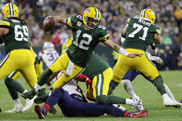 Green Bay Packers quarterback Aaron Rodgers (12) breaks a tackle by New England Patriots linebacker Matthew Judon (9) during overtime in an NFL football game, Sunday, Oct. 2, 2022, in Green Bay, Wis. The Packers won 27-24. (AP Photo/Mike Roemer)