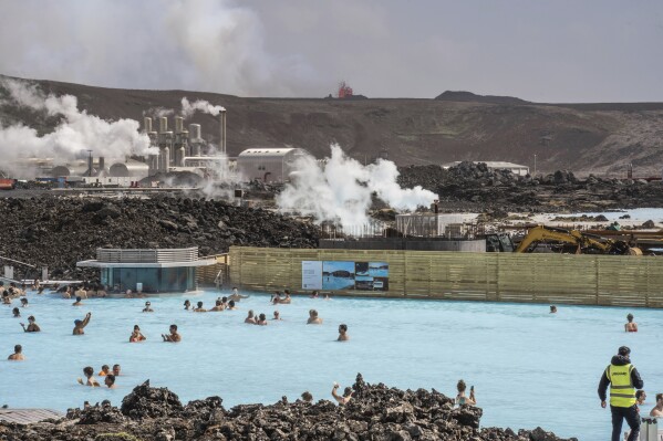 The Blue Lagoon with people bathing in it as the volcanic crater spews lava in the background in Grindavik, Iceland, Sunday, June 2, 2024. The popular Blue Lagoon geothermal spa, one of Iceland’s biggest tourist attractions in the country's southwest, was reopened Sunday after authorities said a nearby volcano had stabilized after erupting four days earlier. (AP Photo/Marco di Marco)