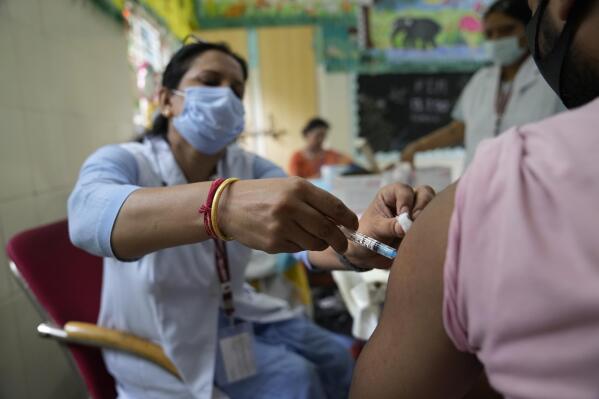 A health worker administers the vaccine for COVID-19 at a vaccination center set up at a government-run school in New Delhi, India, Tuesday, Sept. 21, 2021. India, the world's largest vaccine producer, will resume exports and donations of surplus coronavirus vaccines in October after halting them during a devastating surge in domestic infections in April, the health minister said Monday. (AP Photo/Manish Swarup)