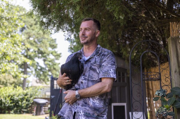Nicholas Olenik holds one of his chickens, named Obama, at their home in Virginia Beach, Virginia on Friday, July 28, 2023. Emus are protector animals so Olenik got chickens for Nimbus to protect and care for. (Kendall Warner/The Virginian-Pilot via AP)