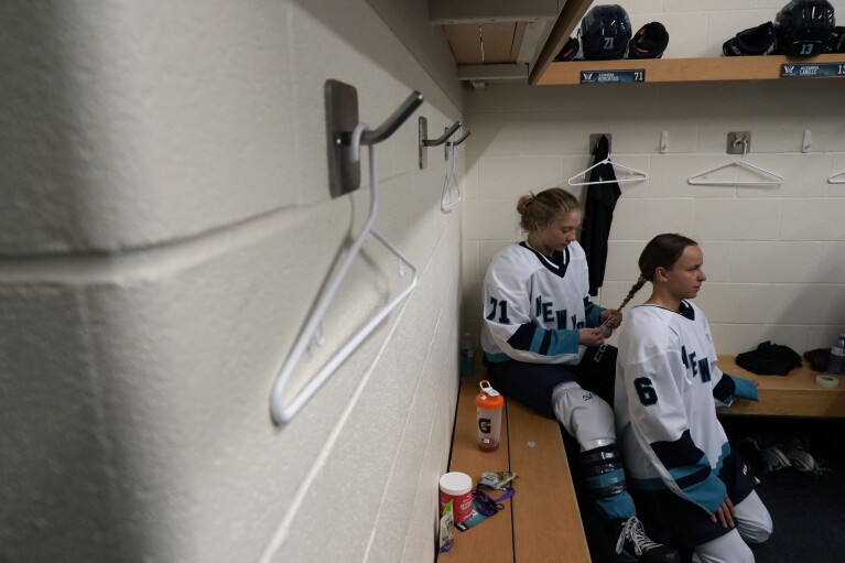 New York Professional Women's Hockey League player Savannah Norcross braids Brooke Hobson's hair in the New York locker room ahead of the inaugural PWHL game in Toronto, Monday, Jan. 1, 2024. (AP Photo/Brittany Peterson)