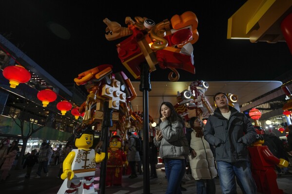 People tour by a dragon made of Lego blocks with the Lunar New Year theme on display at an outdoor shopping mall in Beijing on Feb. 15, 2024. At the start of the Lunar Year of the Dragon, China is seeking to assert its own interpretation of the cultural icon that dates back centuries in both Eastern and Western cultures. (AP Photo/Andy Wong)