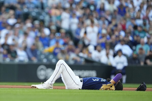 Seattle Mariners shortstop J.P. Crawford lies on the ground after colliding with third baseman Eugenio Suarez as Suarez fielded a grounder by San Diego Padres' Xander Bogaerts, who was out at first during the fourth inning of a baseball game Wednesday, Aug. 9, 2023, in Seattle. (AP Photo/Lindsey Wasson)