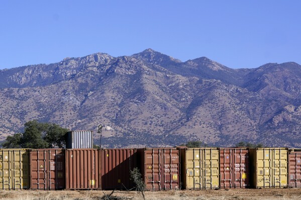 ARCHIVO - Una larga fila de contenedores espera para ser instalada a lo largo de la frontera donde cientos de contenedores crean un muro entre Estados Unidos y México en el Valle de San Rafael, Arizona, el jueves 8 de diciembre de 2022. (AP Foto/Ross D. Franklin)