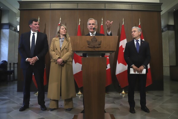 Canada Prime Minister Mark Carney speaks at a press conference while President of the King's Privy Council for Canada Dominic LeBlanc, Minister of Industry Melanie Joly, and Minister of Finance and National Revenue Francois-Philippe Champagne listen, on Parliament Hill in Ottawa, Ontario, Canada, Thursday, June 19, 2025. (Patrick Doyle/The Canadian Press via AP)