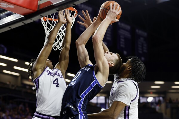 BYU forward Noah Waterman (0) attempts to score as Kansas State guard Dai Dai Ames (4) and forward Will McNair Jr., right, defend during the first half of an NCAA college basketball game, Saturday, Feb. 24, 2024, in Manhattan, Kan. (AP Photo/Colin E. Braley)